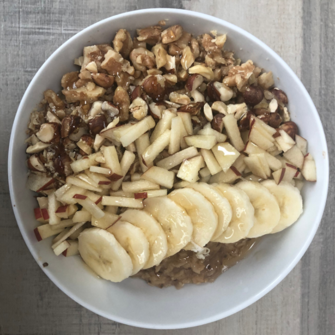 Finished gluten free apple cinnamon oatmeal topped with banana, walnuts, and honey