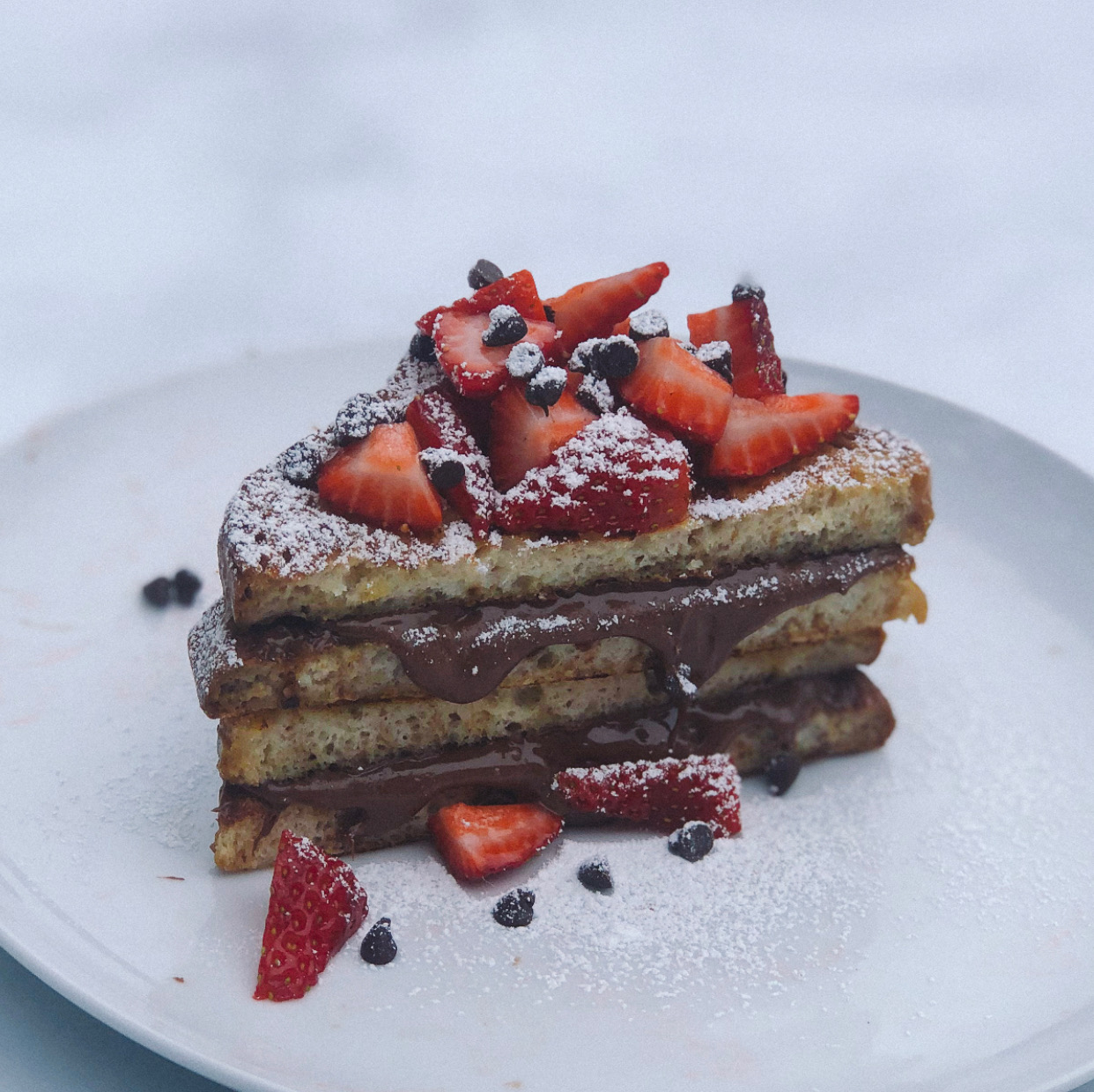 finished plate of gluten free nutella stuffed chocolate french toast with strawberries and chocolate chips