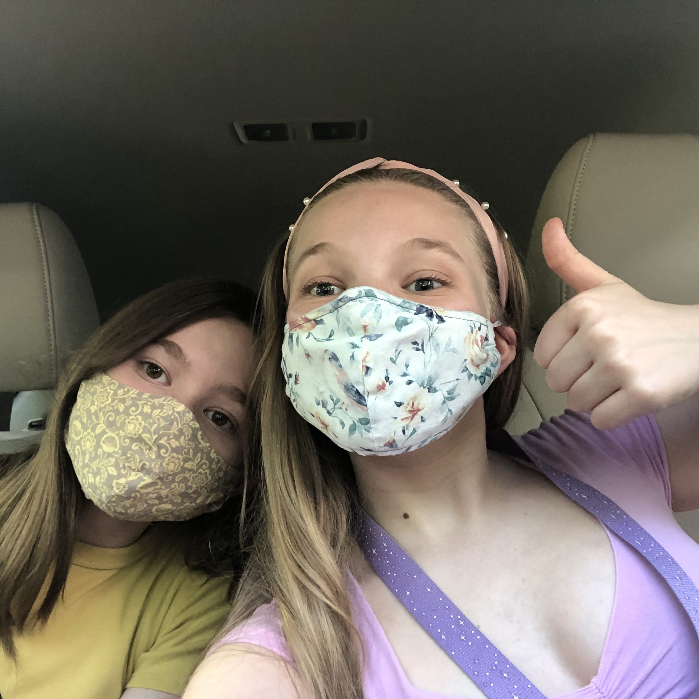 A selfie of me and my little sister, Tess waiting in the line at the Dunkin Donuts drive thru. We are wearing masks and had wipes in the car to disinfect our drinks.