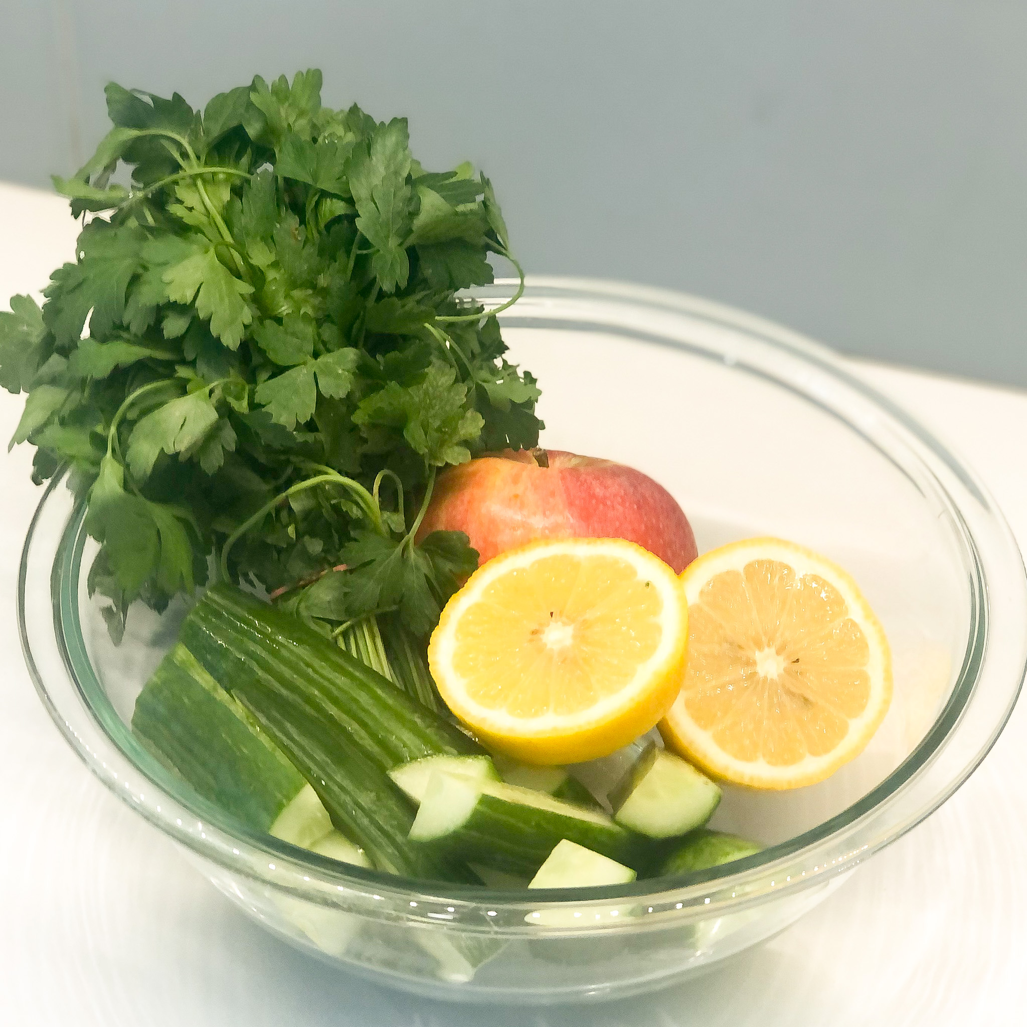 the ingredients to make the green juice: lemon, cucumber, apple, and parsley